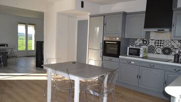 A modern kitchen with grey cabinets, a built-in oven, microwave, and a dining area with a table and chairs.