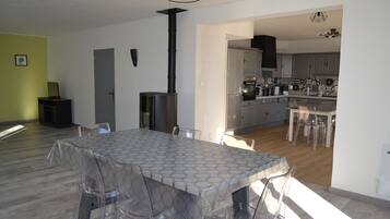A modern kitchen with grey cabinets, a black stove, and a dining area with a glass table and chairs.