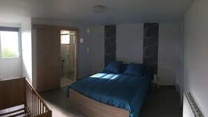 Ein Schlafzimmer mit einem hölzernen Bett, einem kleinen Nachttisch und einer Tür zu einem anderen Raum.