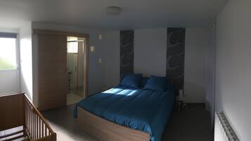 A bedroom with a wooden bed, a small bedside table, and a door leading to another room.