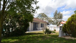 Ein Haus mit einem Ziegeldach, einer überdachten Terrasse und einem Rasen.