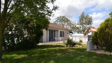 A house with a tiled roof, a covered patio, and a lawn.