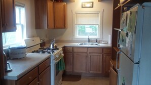 A compact kitchen with wooden cabinets, a stove, a sink, and a refrigerator. - Waterfront cottage on Lake Christopher, screened in porch w/ lake views, firepit (WOODSTOCK)