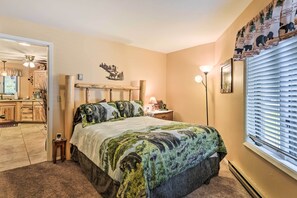 Een slaapkamer met een bed, nachtkastje, lamp en een raam met zonwering.