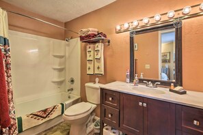 Een badkamer met een bad, toilet, wastafel met spiegel en een handdoekhouder.