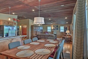 A spacious dining area with a long wooden table, woven placemats, and a hanging light fixture. - The Aviator at Kudzu Cove Cabins Resort (Guntersville)