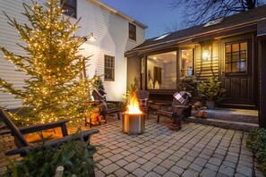 A patio with a fire pit, outdoor seating, and a Christmas tree. - A Modern Antique Home - steps to Dock Square and harbor (Kennebunkport)