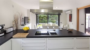 Uma cozinha moderna com ilha central, armários brancos e vista para o exterior.