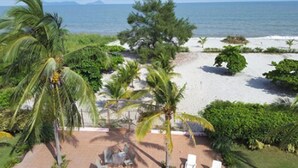 A beach view with palm trees, a sandy area, and a clear sky. - Pink Palace Panama (Punta Chame)