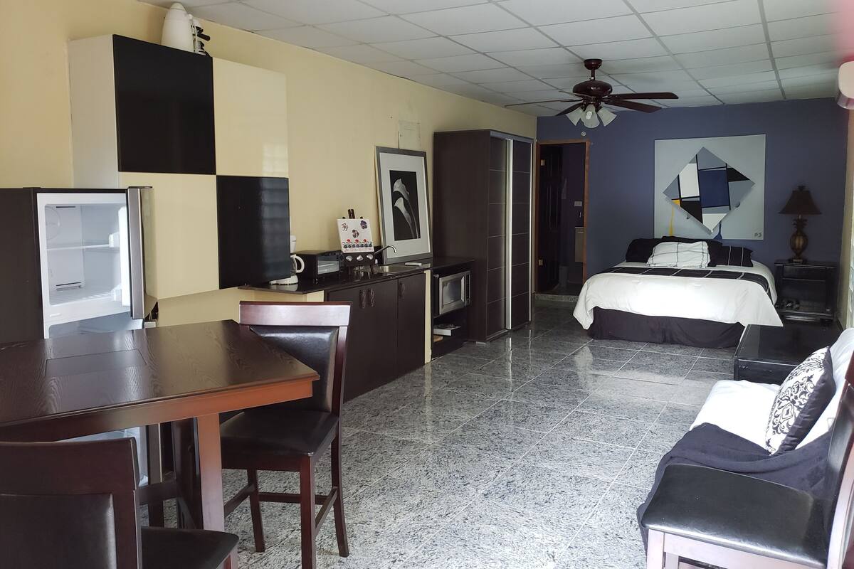 Habitación de hotel con kitchenette, una cama, un escritorio y una silla.