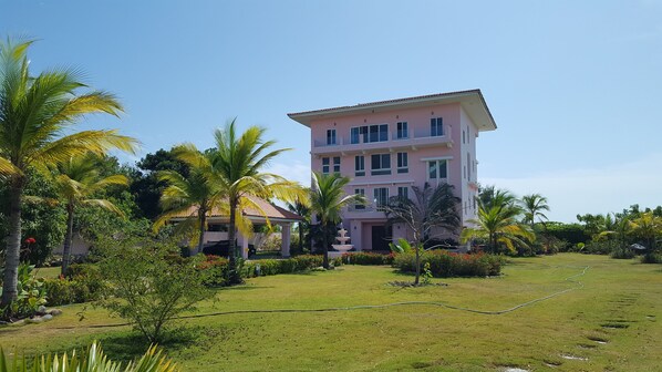 A multi-story building with a flat roof and a garden in front. - Pink Palace Panama (Punta Chame)