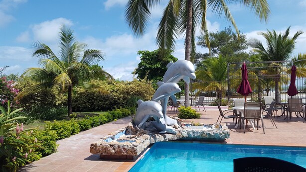 A pool area with dolphin sculptures, palm trees, and outdoor seating. - Pink Palace Panama (Punta Chame)