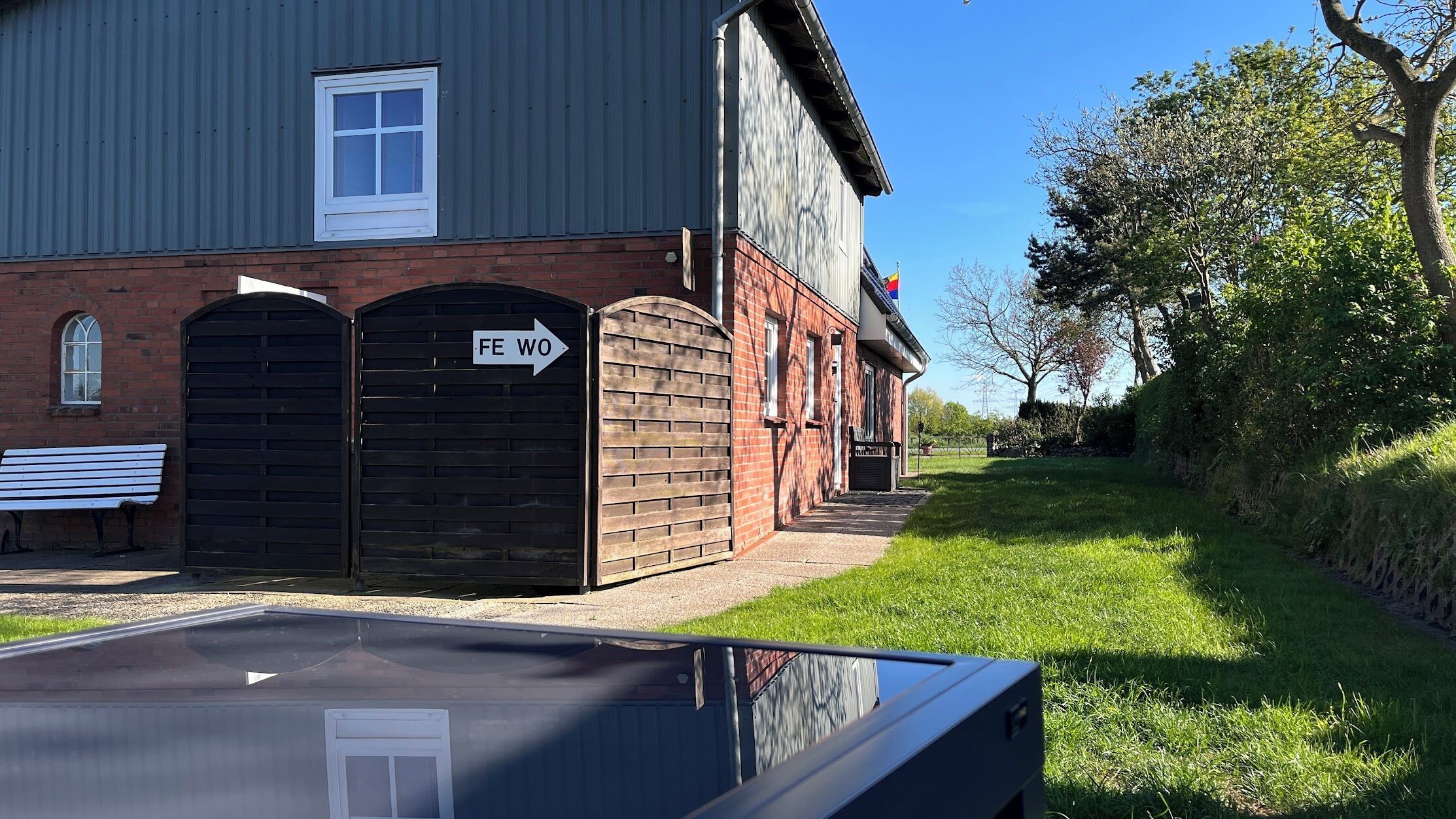 A building with a brick facade, a large wooden gate, and a bench.