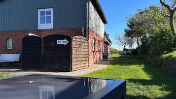 A building with a brick facade, a large wooden gate, and a bench.