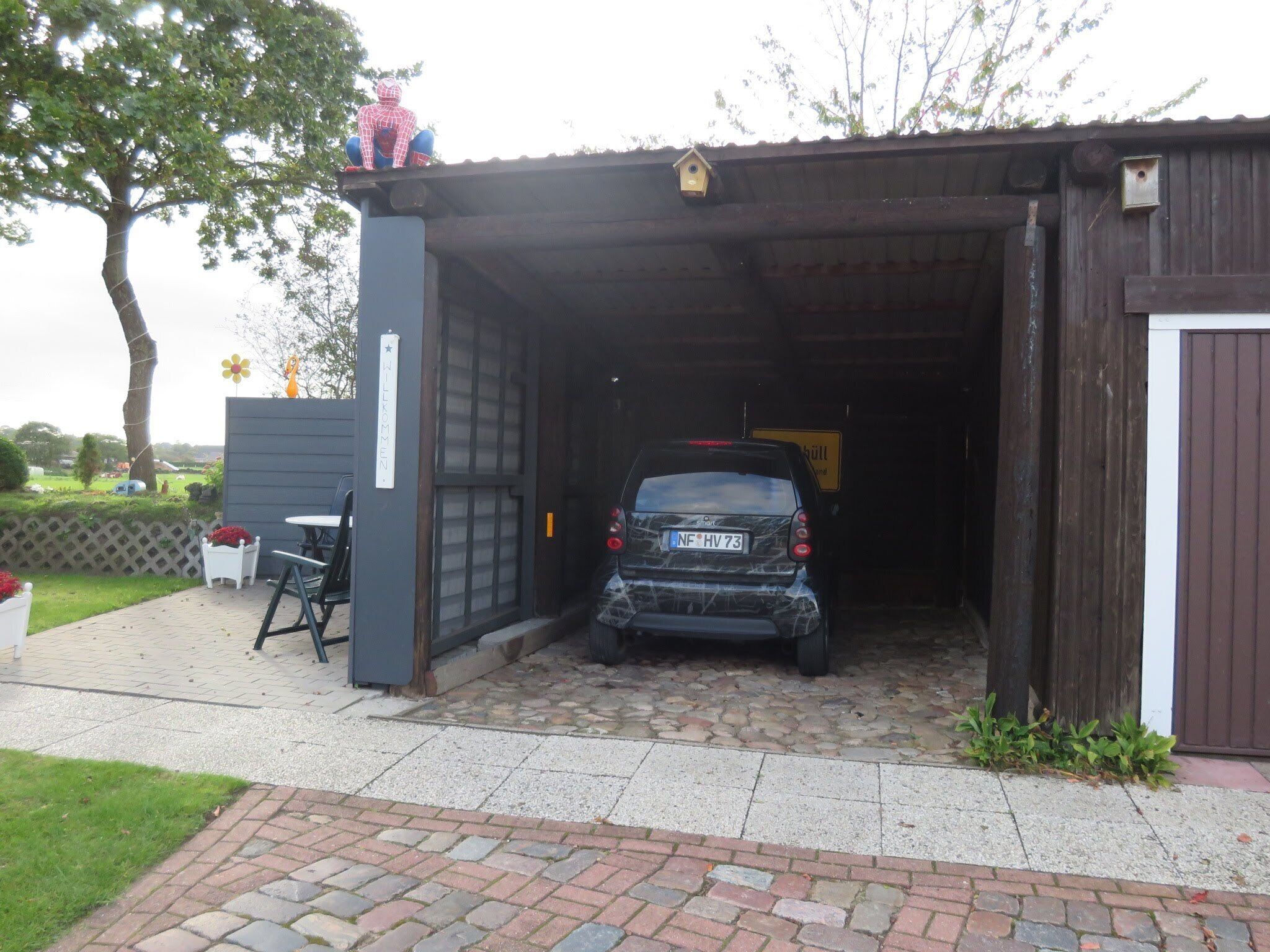 A car parked inside a garage with a wooden door and a small window.