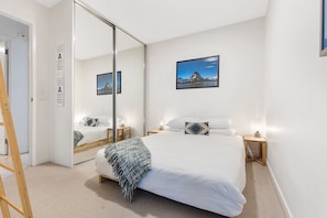 Relax in a serene space with a large bed, two bedside tables, and a large mirror.