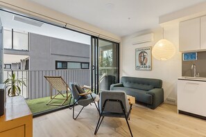 Relax in a spacious living area with a sofa, chairs, and a balcony overlooking the outdoors.