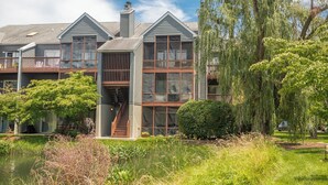 Een tweelaags huis met een balkon, een trap en een vijver op de voorgrond.