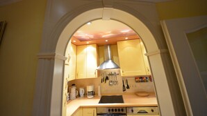 A kitchen with a central island, a stove, and various utensils hanging on the wall.
