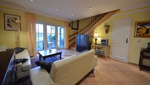 A living room with a sofa, a coffee table, a television, and a staircase leading to an upper floor.