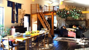 Una sala de estar acogedora con una escalera de madera, una chimenea y un comedor.