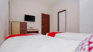 Una camera d'albergo con due letti, una TV a muro, un armadio in legno e una porta.