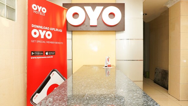 Un'area reception di un hotel con il logo OYO ben visibile e un cartellone pubblicitario per l'app OYO Hotels.