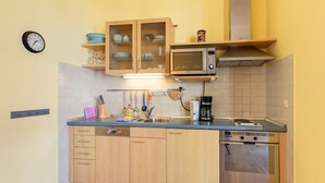 Une cuisine avec des meubles de rangement en bois, un four à micro-ondes, une machine à café et une horloge au mur.