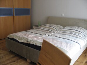 A bedroom with a bed, wooden wardrobe, and a nightstand. - Edelmann apartment, directly to FrankfurtRhineMain (Hörstein)