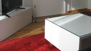 A room with a television on a stand, a white door, and a framed picture on the wall.