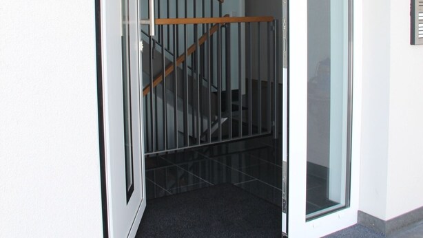 An open sliding door leading to a staircase with a metal railing.