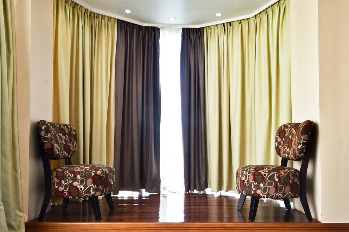 A room with two chairs facing a window with curtains.