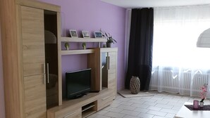 Uma sala de estar com televisão, armário de madeira e sofá.