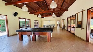A spacious indoor area with a pool table, wooden ceiling beams, and large windows. - 2 bedrooms, 1 suite, 2 bathrooms, 100 m from the best location in Praia da Baleia. (São Sebastião)