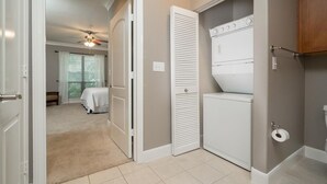 A laundry room with a stacked washer and dryer, a ceiling fan, and a toilet paper holder. - A beautiful codo in the heart of Sugar Land ( Houston suburb) (Sugar Land)