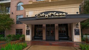 The exterior of City Plaza at Town Square, featuring a brick facade, a covered entrance, and a wooden walkway leading to the entrance. - A beautiful codo in the heart of Sugar Land ( Houston suburb) (Sugar Land)