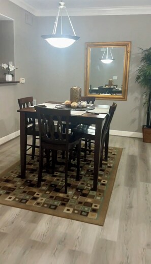 A dining area with a table and chairs, a hanging light fixture, a mirror, and a plant. - A beautiful codo in the heart of Sugar Land ( Houston suburb) (Sugar Land)