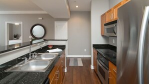 A modern kitchen with stainless steel appliances, wooden cabinets, and a granite countertop. - A beautiful codo in the heart of Sugar Land ( Houston suburb) (Sugar Land)