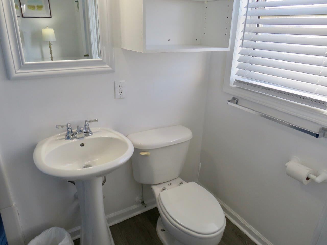 Ein Badezimmer mit Waschtisch, Toilette und einem Fenster mit Jalousien.
