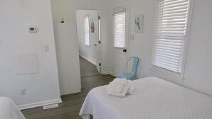 Une chambre à coucher avec un grand lit, une chaise et une porte donnant sur une autre pièce.
