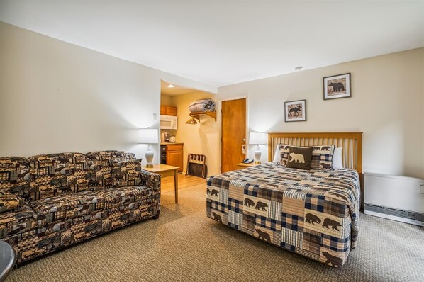 Ein Hotelzimmer mit einer Couch, einem Bett, einem Schreibtisch und einer Küchenzeile.