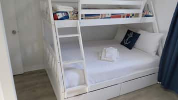 A bunk bed with a ladder, a pillow with an anchor design, and a folded towel on the lower bunk.