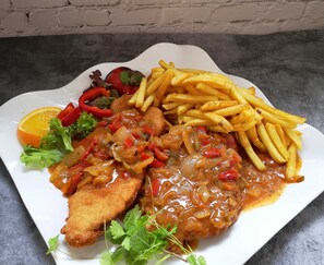 Une assiette de nourriture comprenant du poulet pané, des frites et une salade en accompagnement.