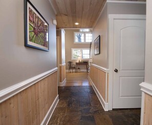 A hallway with wooden paneling, a door, and a table with chairs. - Hot Tub+Fire Pit, Mtn Sunsets, Fireplace & Grill! (Spruce Pine)