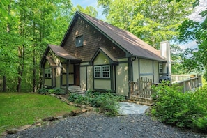 A traditional house with a steep gabled roof, a front porch, and a fenced yard. - Hot Tub+Fire Pit, Mtn Sunsets, Fireplace & Grill! (Spruce Pine)
