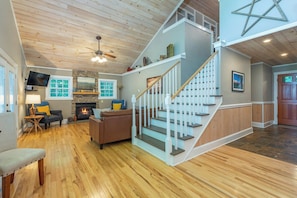 A spacious living area with a fireplace, a staircase, and a television. - Hot Tub+Fire Pit, Mtn Sunsets, Fireplace & Grill! (Spruce Pine)