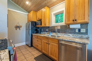 A kitchen with wooden cabinets, a stainless steel refrigerator, a microwave, and a dishwasher.