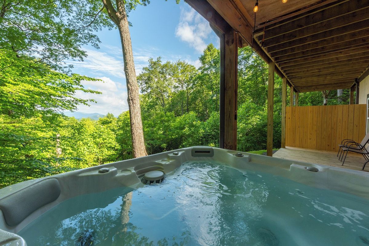 A hot tub in a covered outdoor area with a view of a forest.