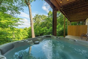 A hot tub in a covered outdoor area with a view of a forest.