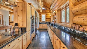 Una cucina in stile baita con mobili in legno, piani di lavoro in granito e pavimento in pietra.